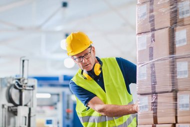 Depo işçisi forklift kullanıyor ve kutuları ayırıyor.