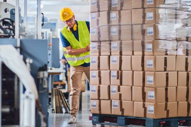 Depo işçisi forklift kullanıyor ve kutuları ayırıyor.