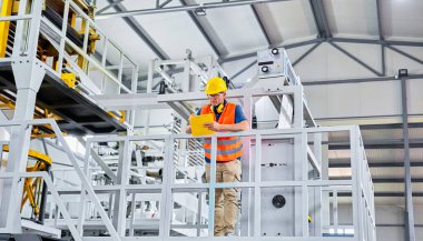 Fabrikadaki üretim hattı. Endüstriyel tesis veya kamu hizmetlerindeki ekipmanları kontrol eden veya ayarlayan teknisyen veya mühendis