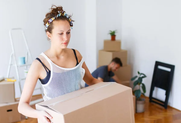 Moving out. Young woman carrying cardboard box felling tired