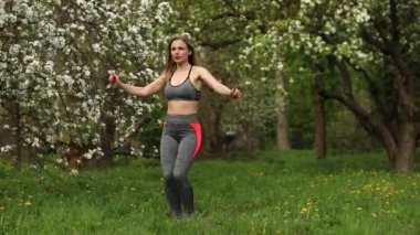 Güzel görünümlü atletik kadın parkta dışarıda egzersiz yapıyor. Sportif kadın bacak sallama, atlama ve kardiyo egzersizleri yapıyor.. 