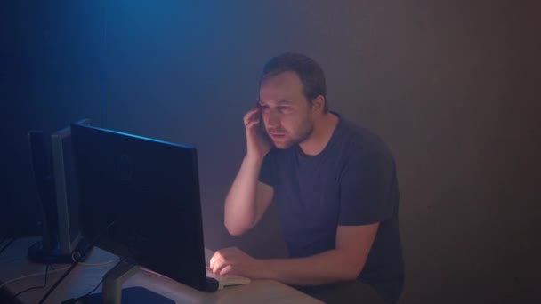 Man geek hacker travaille à l'ordinateur dans la salle de bureau souterraine sombre avec des écrans d'affichage. Homme Hacker fait son travail avec soin et étirer sa colonne vertébrale de la fatigue .