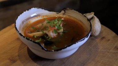 Bouillabaisse çorbası ahşap arka planda dönüyor. Geleneksel Fransızca, Akdeniz çorbası et suyu, balık, mürekkep balığı, karides, kabuk ve maydanozla kaplı. Menü sunumu.