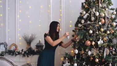 Çekici bayan, Noel ağacını gülerek değil, lüks içinde süslüyor. Güzel esmer bayramları kutluyor. 