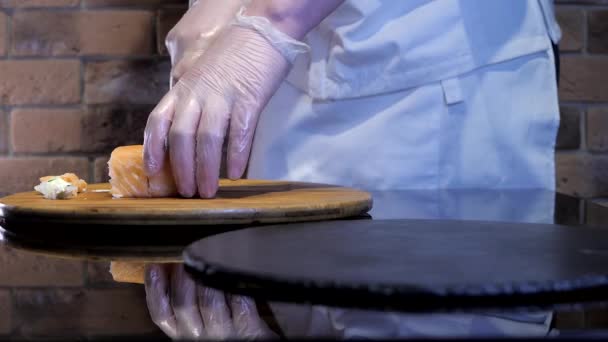 Sushi chef-kok snijdt Philadelphia en zet de maaltijd op de zwarte plaat. — Stockvideo