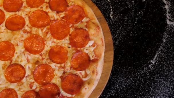 Vista dall'alto della pizza al salame piccante sul piatto di legno ruota sullo sfondo scuro. — Video Stock