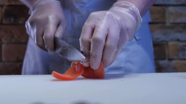 トマトを切るシェフの視点を閉じ 料理のための食材を準備します シェフは手袋とエプロンをしています — ストック動画