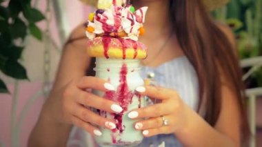 Çok katmanlı milkshake içen çekici bir kadının yakın görüntüsü. Yaz zamanı, açık havada. 