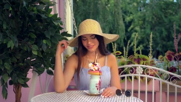 Mujer de moda en sombrero de ala ancha está pasando tiempo al aire libre en la cafetería de la ciudad — Vídeo de stock