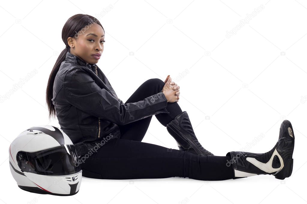 Black female racer or biker or stuntwoman sitting with a racing helmet and gear.  The gritty woman driver is isolated on a white background.
