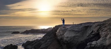 Gün batımı sırasında Kaliforniya'daki Malibu beach kıyı şeridi boyunca buzlu bekleyen bir cep telefonu ile mobil fotoğrafçılık yaptığını Turizm.  