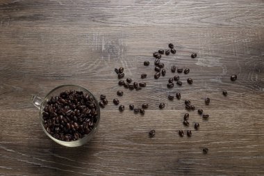 Ahşap bir masaya boşaltmak veya metin için düzenlenmiş koyu kavrulmuş kahve çekirdekleri fincan