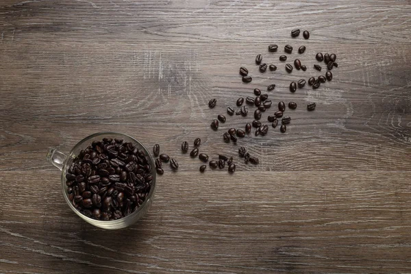 Stock image Cup of dark roasted coffee beans arranged on a wooden table for copyspace or text