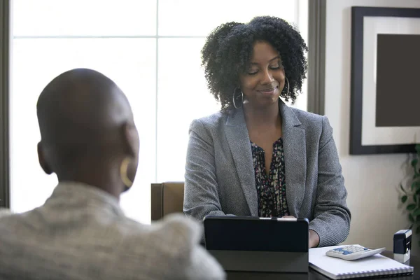 Couple of black female businesswomen or partners arguing at work or a bossy manager doing a job interview or perfomance review to an employee and looking disappointed.