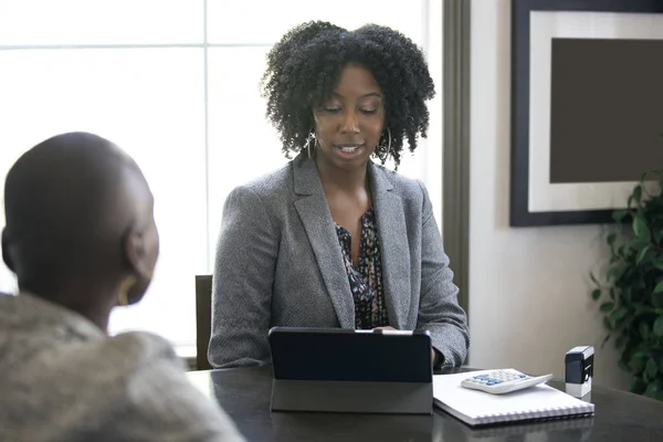 Black female businesswoman in an office with a client giving legal advice about taxes or financial loans. The woman could be a lawyer or a cpa accountant.