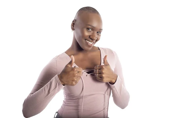 黑人非洲裔美国女模特与秃头发型穿着粉红色的衬衫在白色背景做竖起大拇指 — 图库照片