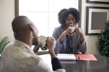 Siyah-Afro-Amerikan kadın iş kadınları bir ofiste konuşuyor. İki kadın bir start up iş arkadaşları ya da küçük iş ortakları gibi görünüyor.  