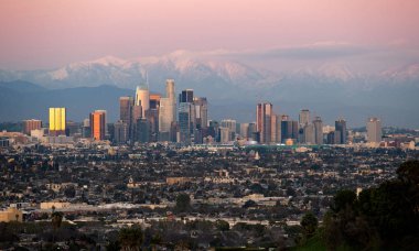 Los Angeles California şehrinin panoramik manzarası, iklim değişikliği nedeniyle kuraklığın sona erdiğini gösteren karlı dağ kapakları ile. Geniş görünümü Hollywood ve Downtown gösterir.