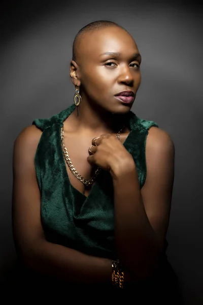 Black African American female fashion model with a bald hairstyle in a studio.  The portrait shows the beauty and confidence of the bold and trendy glamour hairdo style.