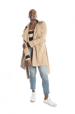 Kendine güvenen siyah Afrikalı-Amerikalı kadın model bir ceket veya ceket ve kot pantolon ile Sonbahar veya Bahar tarzı moda giyiyor. O kel bir saç modeli ve beyaz bir arka plan üzerinde izole.  