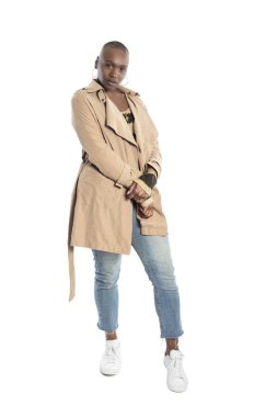 Kendine güvenen siyah Afrikalı-Amerikalı kadın model bir ceket veya ceket ve kot pantolon ile Sonbahar veya Bahar tarzı moda giyiyor. O kel bir saç modeli ve beyaz bir arka plan üzerinde izole.  