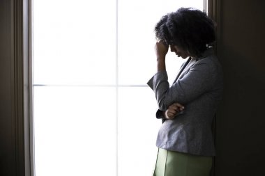 Siyah-Amerikalı bir iş kadını siluet endişeli görünümlü ve ofis penceresi tarafından sorunları ve başarısızlık hakkında düşünme. O depresif ya da borç veya iflas hakkında üzgün görünüyor.