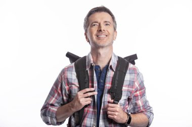 Orta Yaşlı adam yürüyüş veya trekking ya da seyahat ederken bir turist olarak yürüyüş tarafından emeklilik sırasında sağlıklı aktiviteler yapıyor. O beyaz bir arka plan üzerinde bir sırt çantası taşıyan kendinden emin ve mutlu görünüyor.