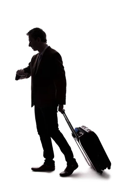 出張や荷物を持って旅行するビジネスマンのシルエット 男は空港で飛行機に乗る準備のようなバッグを運んでいる — ストック写真
