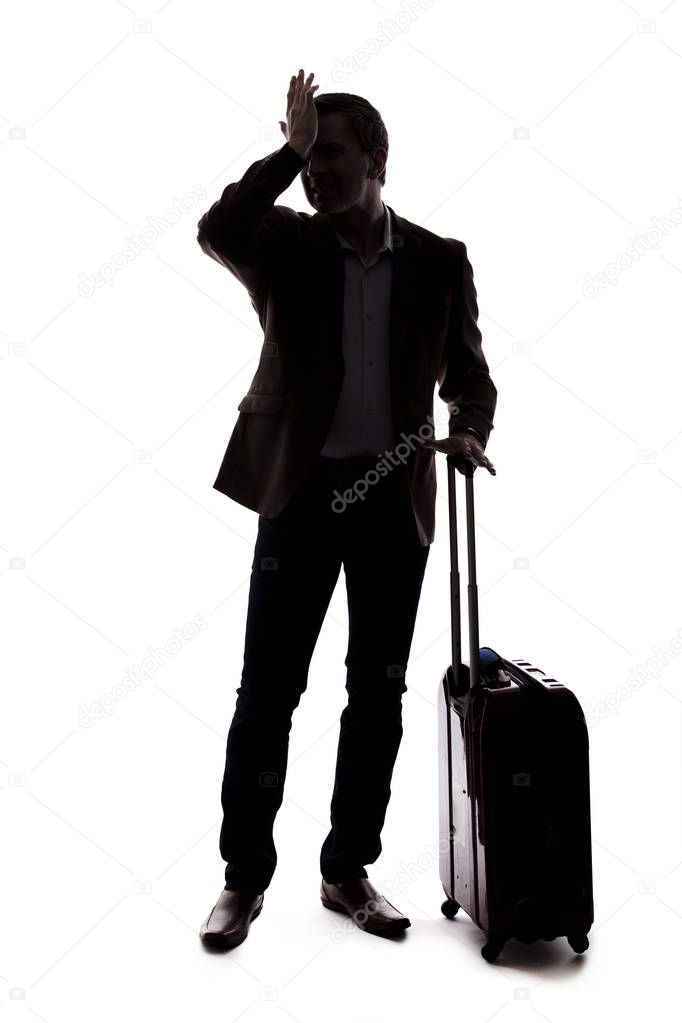 Silhouette of a traveling businessman looking upset because of a delayed or cancelled flight.  The traveler is stressed and waiting with his luggage.  Isolated on a white background.