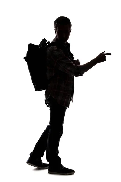 男性ツアーガイドのシルエットハイキングと白い背景にバックパックを運ぶ 彼は何かを指差している 冒険と探検を描く — ストック写真