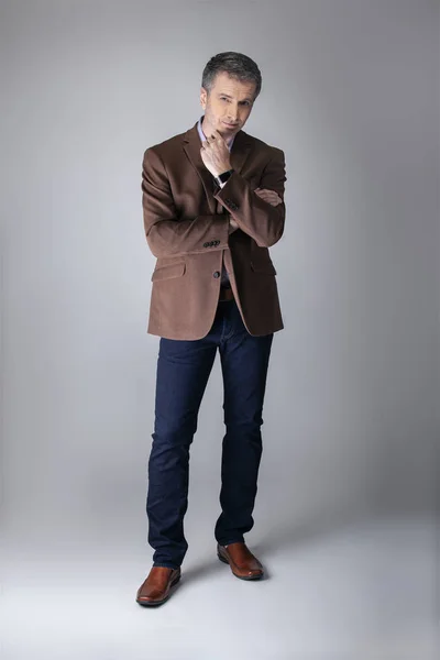 stock image Bearded middle aged fashion model posing with business casual style outfit for mature and confident look.  The trendy brown jacket and jeans and facial hair shows an elegant apparel.