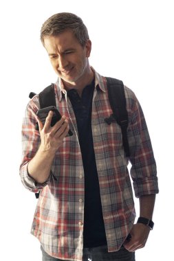 Yürüyüşçü yol tarifi veya yardım istemek için bir telefon görüşmesi yapmak için bir cep telefonu kullanarak. Beyaz arka plan üzerinde izole edilmiş ve kompozitler için gün batımı ışığı ile aydınlatılmış. 