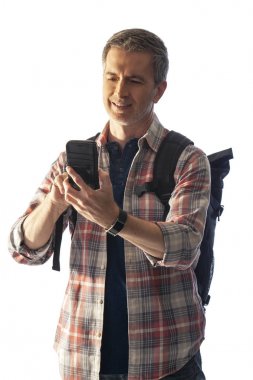 Yürüyüşçü yol tarifi veya yardım istemek için bir telefon görüşmesi yapmak için bir cep telefonu kullanarak. Beyaz arka plan üzerinde izole edilmiş ve kompozitler için gün batımı ışığı ile aydınlatılmış. 