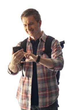 Yürüyüşçü yol tarifi veya yardım istemek için bir telefon görüşmesi yapmak için bir cep telefonu kullanarak. Beyaz arka plan üzerinde izole edilmiş ve kompozitler için gün batımı ışığı ile aydınlatılmış. 