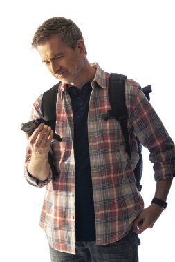 Yürüyüşçü yol tarifi veya yardım istemek için bir telefon görüşmesi yapmak için bir cep telefonu kullanarak. Beyaz arka plan üzerinde izole edilmiş ve kompozitler için gün batımı ışığı ile aydınlatılmış. 