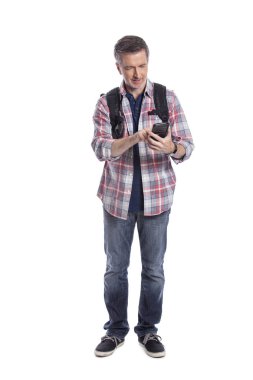 Erkek turist ya da bir yürüyüşçü aramak için bir cep telefonu kullanarak ya da o seyahat böylece bir rideshare mesaj. Adam sırt çantası giyiyor ve akıllı telefon kullanıyor. Beyaz arka planda yalıtılmış. 