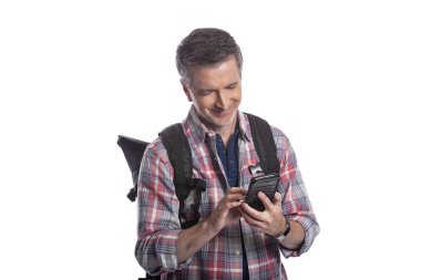 Erkek turist ya da bir yürüyüşçü aramak için bir cep telefonu kullanarak ya da o seyahat böylece bir rideshare mesaj. Adam sırt çantası giyiyor ve akıllı telefon kullanıyor. Beyaz arka planda yalıtılmış. 