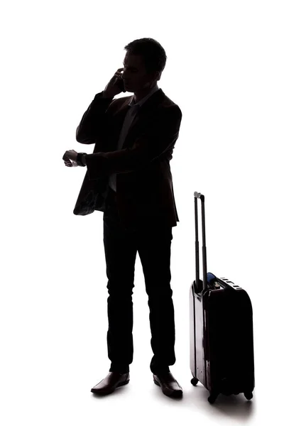 一个商人的剪影 他打电话用手机拼车 他提着行李等着 好像是从机场来的一样 复合材料在白色背景上隔离 — 图库照片