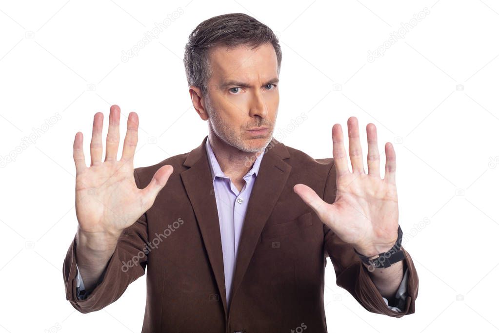 Middle aged bearded businessman on a white background wearing a brown jacket.  The mature man looks like a business executive holding hands up for stop gesture.