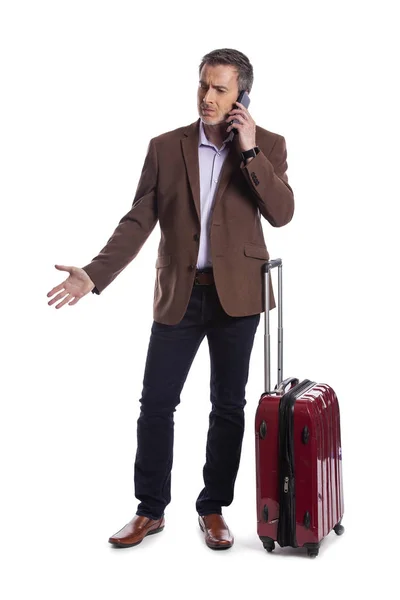 商人在电话中抱怨取消航班或要求晚点乘坐共享航班 他正带着行李等着 好像他刚到或准备出发 — 图库照片