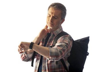 Orta yaşlı yürüyüşçü bir akıllı saat sağlık uygulamaları ile kalp hızı nabız kontrol. O commposite arka planlar ile uyum için günbatımı ışık ile aydınlatılmış.