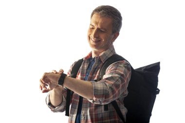 Orta yaşlı yürüyüşçü bir akıllı saat sağlık uygulamaları ile kalp hızı nabız kontrol. O commposite arka planlar ile uyum için günbatımı ışık ile aydınlatılmış.