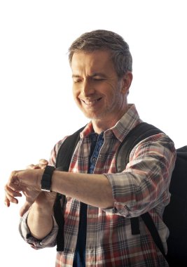 Orta yaşlı yürüyüşçü bir akıllı saat sağlık uygulamaları ile kalp hızı nabız kontrol. O commposite arka planlar ile uyum için günbatımı ışık ile aydınlatılmış.