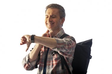 Orta yaşlı yürüyüşçü bir akıllı saat sağlık uygulamaları ile kalp hızı nabız kontrol. O commposite arka planlar ile uyum için günbatımı ışık ile aydınlatılmış.