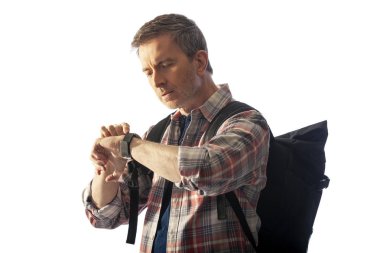 Orta yaşlı yürüyüşçü bir akıllı saat sağlık uygulamaları ile kalp hızı nabız kontrol. O commposite arka planlar ile uyum için günbatımı ışık ile aydınlatılmış.