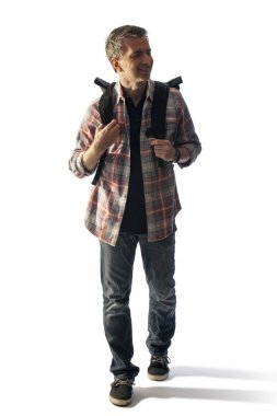 Gün batımında yürüyen bir sırt çantası ile Orta Yaşlı erkek turist. Kompozitler için beyaz bir arka plan üzerinde izole edilmiş. Bu yaşlı olgun erkekler için sağlıklı yaşam tarzı faaliyetleri tasvir. 