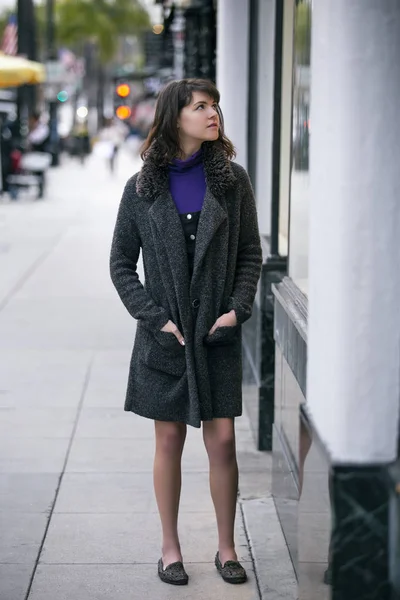 Şehirde dışarıda yürüyen bir kadın. O vitrin alışveriş ve bir mağaza satış reklam veya pazarlama giyim ve giyim bir ekran cam bakıyor. 