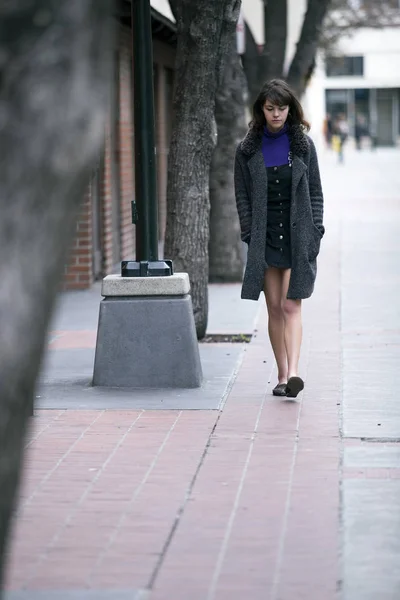 都会の歩道や舗装街の公園を歩く若いかわいい女性 彼女は独立したミレニアル世代の女性観光客のように見えます 徒歩でソロ旅行コートを着て — ストック写真