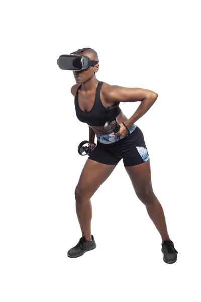 Athletic black female gamer wearing a vr headset and exercising in a virtual reality gym for weight loss.  The image depicts technology used in sports and esports entertainment for healthy lifestyle.