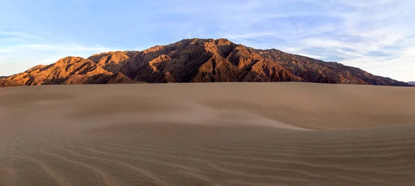 Sand dunes in a desert landscape in Death Valley California.  The vast barren land is dry and arid due to droughts result of global warming and climate change.